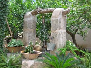 Mit der richtigen Dekoration fügt sich der Brunnen gut in den Garten ein. Bild Steinbrunnen mediterraner Garten